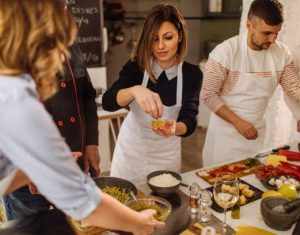 Photo of a young woman in a kitchen during a cooking class, preparing bruschetta
